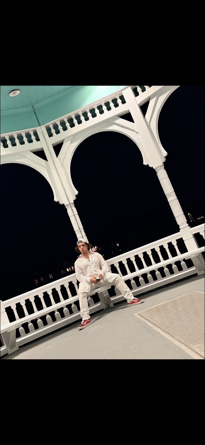 Sullivan McCusker seated on a porch wearing a white outfit